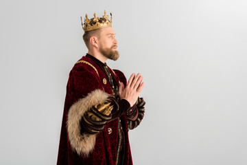 side view of king with crown praying isolated on grey - obrazy, fototapety, plakaty