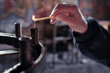 Woman's hand lighting candle at church shrine for the living