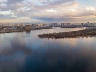 Aerial drone view. View of the Dnieper and the left bank of Kiev in the sunset. The sky is reflected in the water.