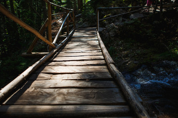 Wooden bridge with steps on the eco-trail along the rocks and mountain river in Bulgaria, Smolyan city. Equipped tourist road through the forest for sightseeing tours and walks