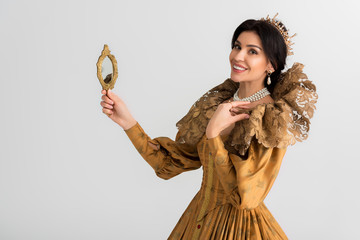 smiling queen with crown holding mirror isolated on grey © LIGHTFIELD STUDIOS