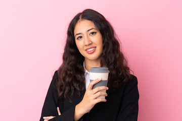 Mixed race business woman holding coffee to take away over isolated pink background