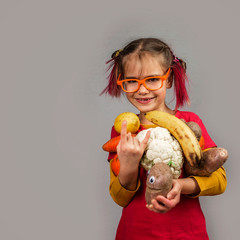 Freakish kid holds misshapen wrong color fruits and vegetables, waste food concept