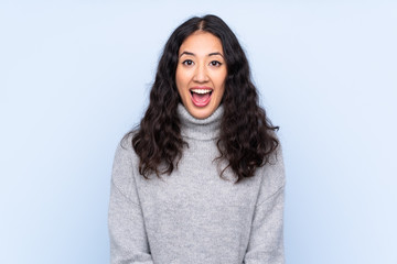 Spanish Chinese woman over isolated blue background with surprise facial expression