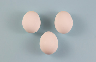 Three white chicken eggs on a blue background. place for text, easter holiday concept