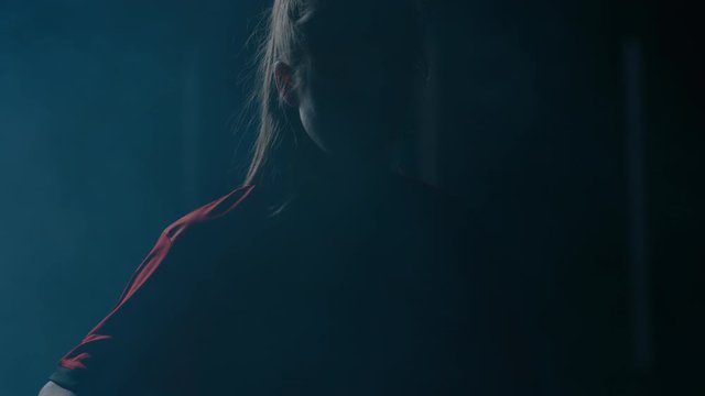 Dramatic portrait of teenager girl soccer player holding a ball, posing in a generic uniform against bright flashing lights. Shot on ARRI Alexa Mini 60 FPS slow motion