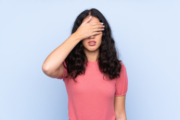 Mixed race woman wearing a sweater over isolated blue background covering eyes by hands