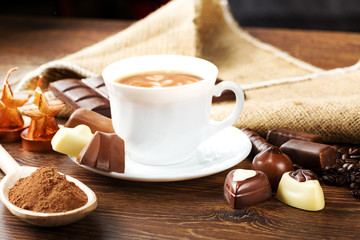 cup of delicious latte with chocolate and roasted coffee beans covered in burlap