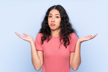 Mixed race woman wearing a sweater over isolated blue background having doubts with confuse face expression