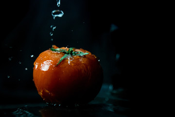 Czerwony pomidor polewany wodą, czarne tło