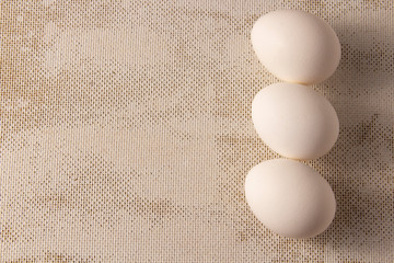 Three white chicken eggs on a blue background. place for text, easter holiday concept