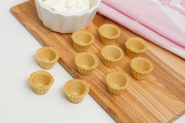 Tartlets with custard or cottage cheese. Empty tartlets or pie on a white table. Food lay flat. The view from the top. The concept of preparing food for the holiday table.