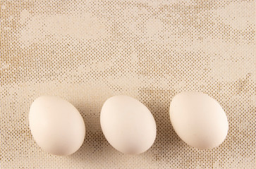 Three white chicken eggs on a blue background. place for text, easter holiday concept