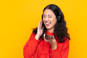Mixed race woman wearing a red sweatshirt listening music with a mobile and singing