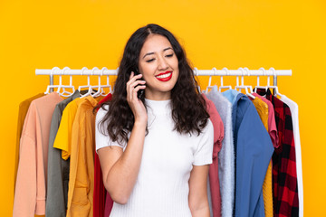 Mixed race woman in a clothing store and talking to mobile