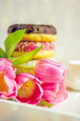 Obraz na płótnie Canvas Sweet donuts in glaze and pink tulips background