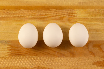 Three white chicken eggs on a wooden background. place for text, easter holiday concept