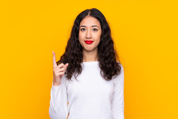 Mixed race woman over isolated yellow background pointing with the index finger a great idea