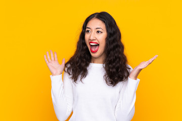 Mixed race woman over isolated yellow background with surprise facial expression