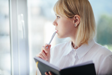 Woman in office working, writing in notepad