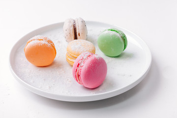 Colorful French macaron or Italian macaron stack on white plate put on white background with copy space for background or wallpaper. Flat lay.
