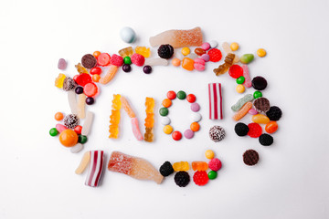 Concept no sweets, colorful candies, jelly and marmalade on white background. Flat lay, top view