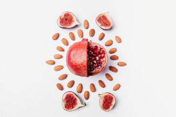 Sliced red pomegranate fruit with almonds on pastel white background. Minimal flat lay concept. Pastel colors.