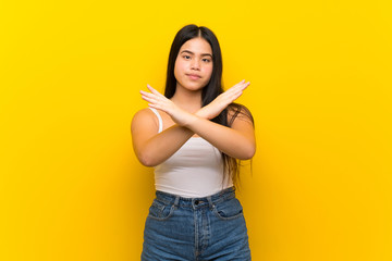 Young teenager Asian girl over isolated yellow background making NO gesture