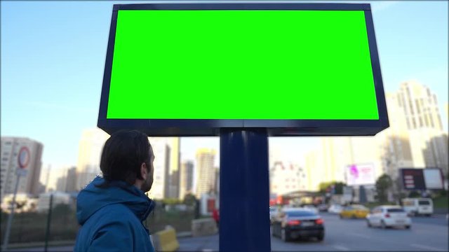 Green screen billboard on urban, street traffic. Cars are going and empty, blank chroma key signboard for marketing. 
