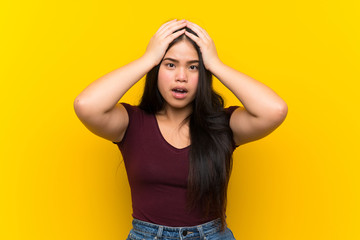 Young teenager Asian girl over isolated yellow background with surprise facial expression