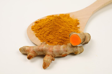 Turmeric powder in a wooden spoon and turmeric root extracted on a white background, used as a...