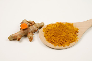 Turmeric powder in a wooden spoon and turmeric root extracted on a white background, used as a tonic for the body and food ingredients.