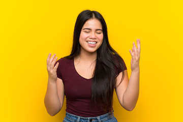Young teenager Asian girl over isolated yellow background laughing