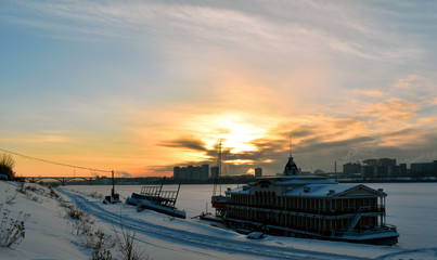Fototapeta na wymiar sunset over a frozen river in the city