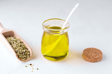 hemp oil next to peeled hemp seeds on a white background.