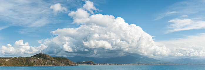Panoramic view of the Milazzo coast with large white clouds above. Slightly noisy photography. Milazzo, Sicily, Italy