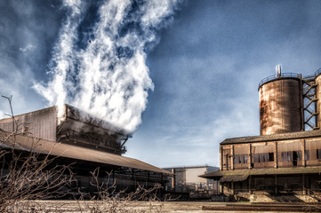Fototapeta na wymiar Antigua fabrica vieja medio abandonada, sale humo blanco, parece vapor