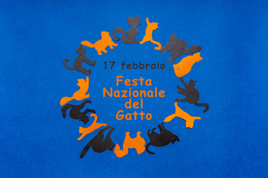 Happy Cat Day in Italy. Round frame made of orange and black funny cat silhouettes on blue background. Festive layout for feline holiday, text in Italian 17 FEBRUARY NATIONAL CAT DAY. Flat lay