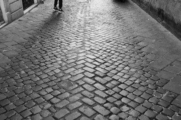 Black and White, people crossing the street on zebra crossing with shadow. Silhouette shadow of people walking on street floor. People Walking on a cobblestone pavement.