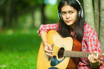 asian girl playing guitar and singing in the park happy weekend