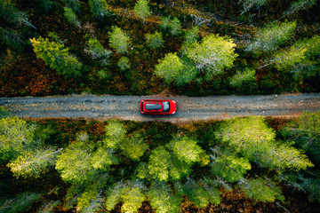 Aerial view of red car with a roof rack on a country road in Finland
