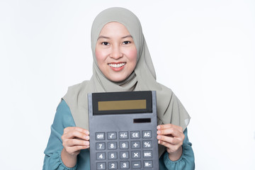 Female muslim holding a big calculator with facial expression - financial concept.