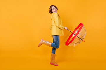 Full-length photo of pleased girl in trendy autumn jacket standing on one leg. Excited european...