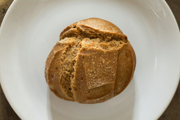 Soft fresh baked white bread with a crispy crust on a white plate on textured table