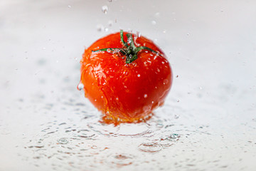 Świeży pomidor widziany z boku, polewany wodą © andsko