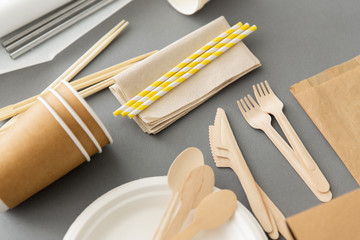 recycling, tableware and eco friendly concept - disposable dishes of paper and wood on grey...