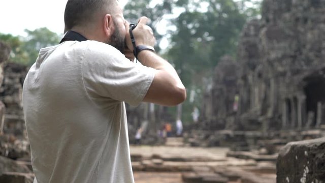 Man taking photos, sightseeing ancient Angkor Wat temple ruins in Cambodia