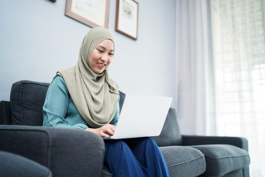 Female muslim using laptop at home environment.