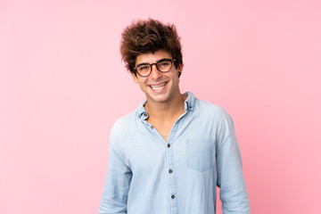 Young caucasian man with jean shirt over isolated pink background with glasses and happy