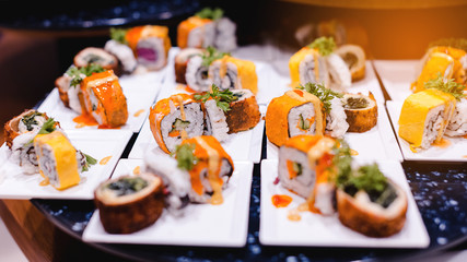 Lot of sushi rolls on desk.